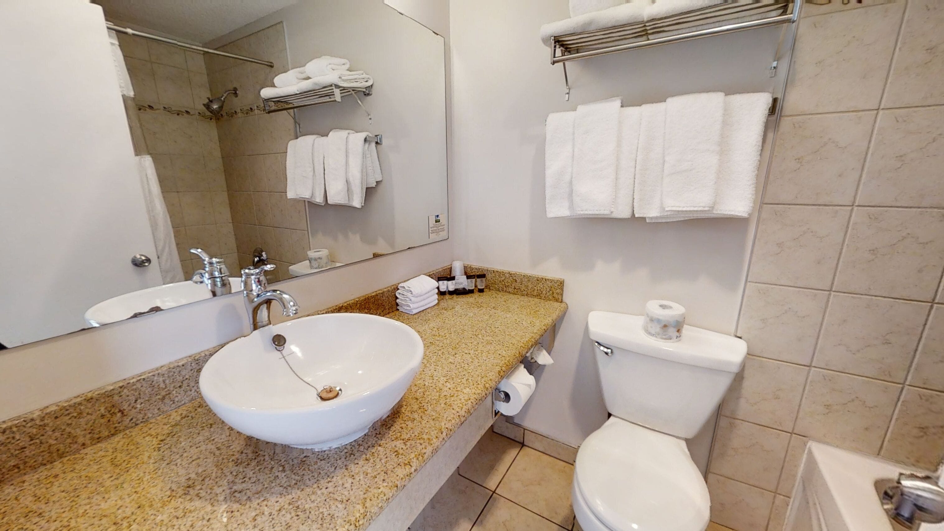 A bathroom with a sink, mirror, toilet, and towel rack.