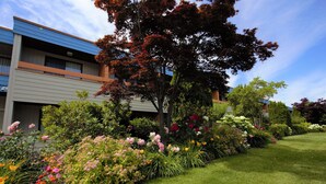 A modern building with a well-maintained garden featuring various flowers and shrubs. - Recreation Inn & Suites (Kelowna)