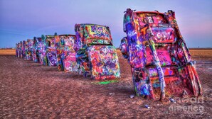 A row of colorful, graffiti-covered vehicles parked in a barren landscape. - Hawthorn Extended Stay by Wyndham Amarillo (Amarillo)