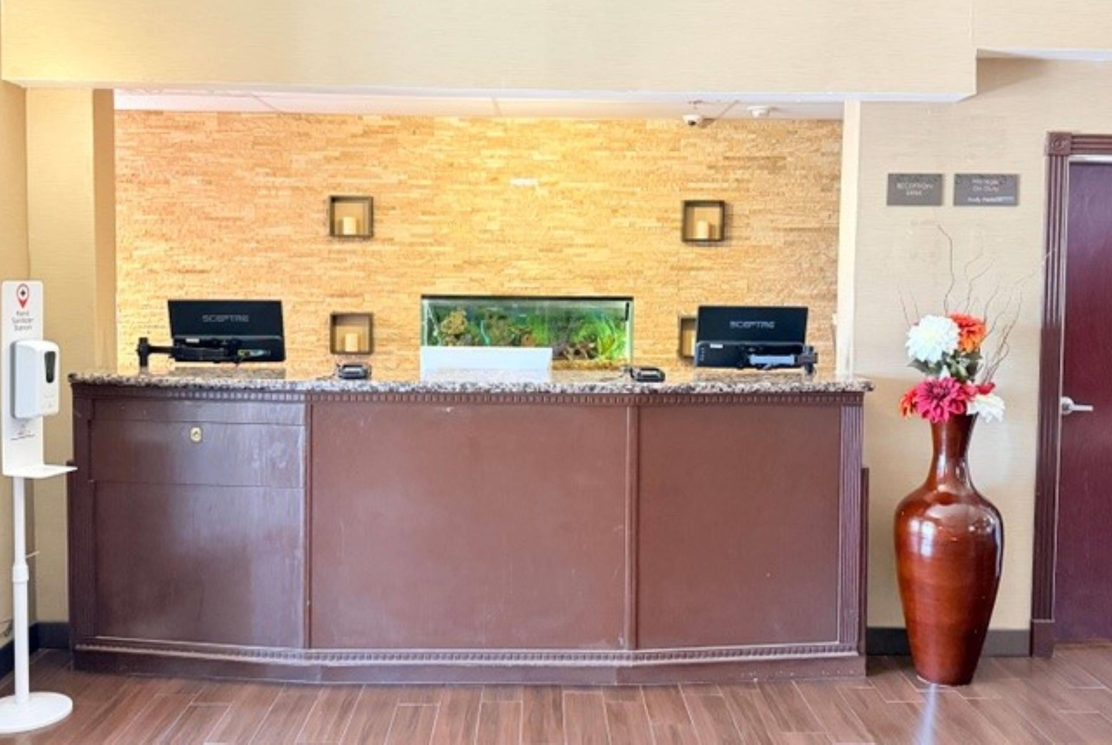 A reception desk with a stone wall backdrop, a fish tank, and a vase with flowers.