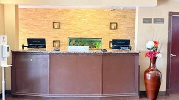 A reception desk with a stone wall backdrop, a fish tank, and a vase with flowers.