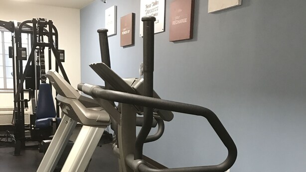 A gym with treadmills and weight machines, a blue wall with motivational signs, and a window with natural light. - Hawthorn Extended Stay by Wyndham Amarillo (Amarillo)