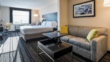 A hotel room with a bed, a sofa, a desk, and a window.