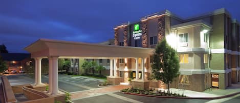 A Holiday Inn Express hotel with a covered entrance, outdoor seating area, and a parking lot.