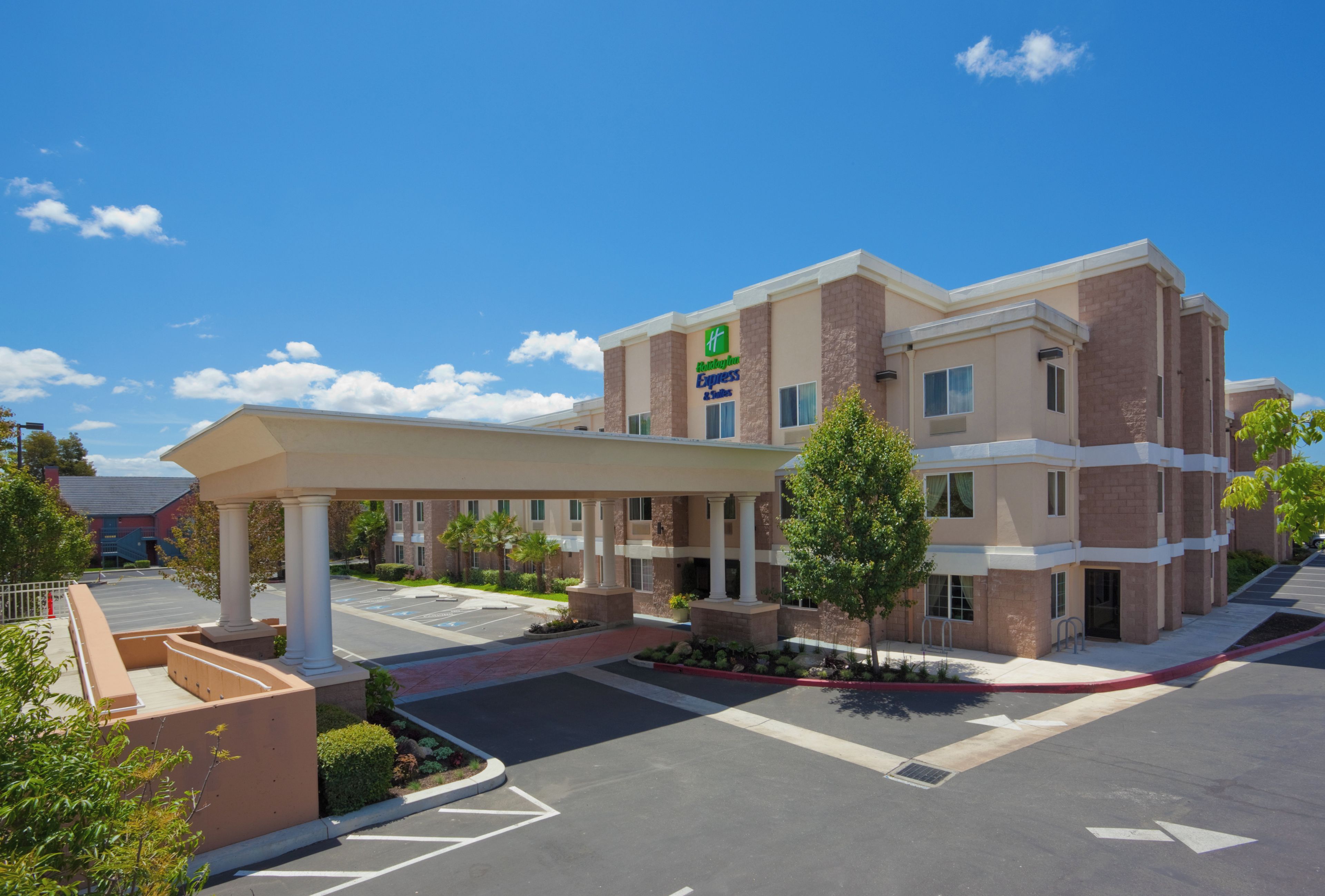 A hotel with a covered entrance, multiple floors, and a parking lot.