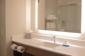 A hotel bathroom with a large mirror, a sink, and two rolls of toilet paper. - Holiday Inn Express Hotel & Suites Livermore by IHG (Livermore)