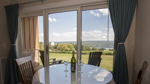 A round table with a glass top, two chairs, a bottle of wine, and two wine glasses. - The Inn at Glenora Wine Cellars (Dundee)