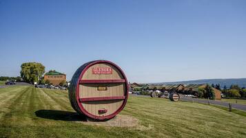 A large wooden barrel labeled "Glenora Wine Cellars" in a grassy field with a building and trees in the background.