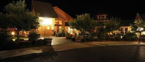 A well-lit hotel with a prominent entrance, landscaped gardens, and a clear driveway.