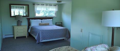 A bedroom with a bed, nightstand, chair, and a window with curtains.