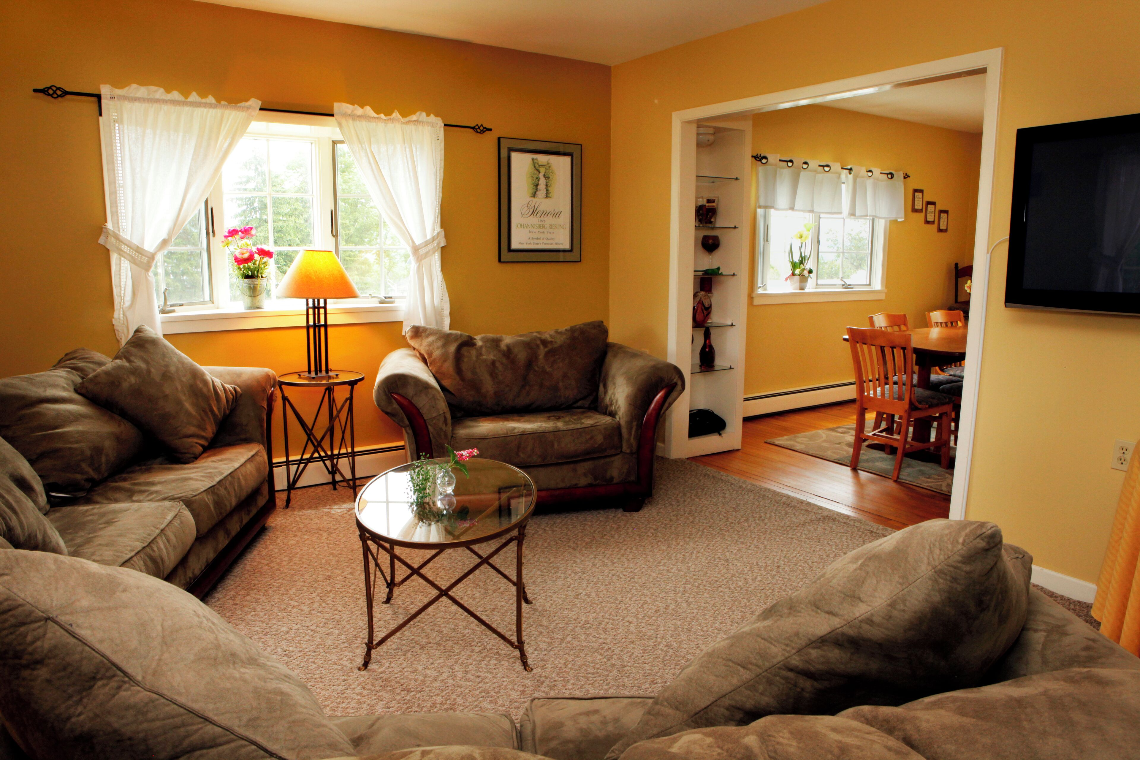 A living room with two sofas, a glass coffee table, and a dining area with a table and chairs.