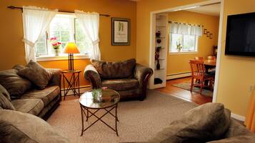A living room with two sofas, a glass coffee table, and a dining area with a table and chairs.