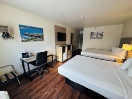 Habitación de hotel con cama, escritorio, silla y televisión.
