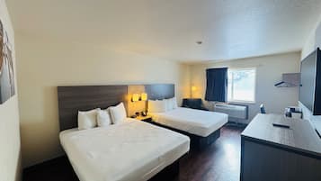 Habitación de hotel con dos camas, un escritorio, una silla, un televisor y una ventana con cortinas.