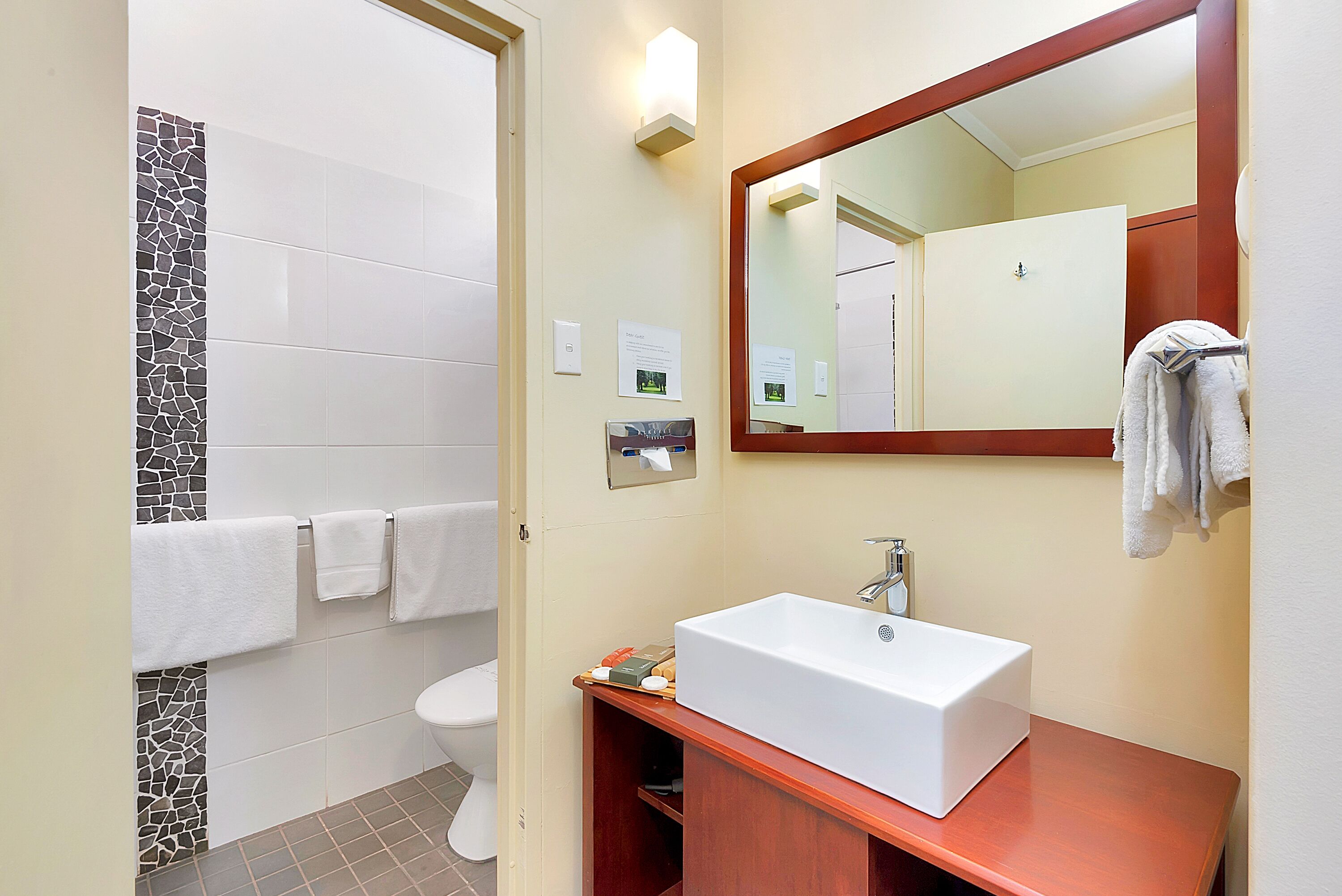 A bathroom with a white sink, a mirror, a towel rack, and a toilet.