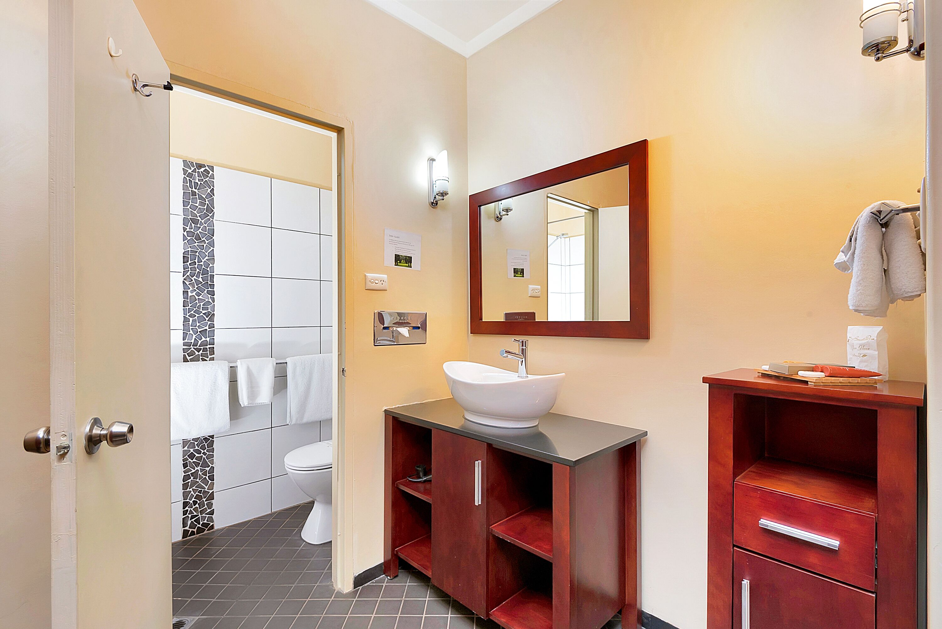 Un baño con lavamanos blanco, tocador de madera y espejo.