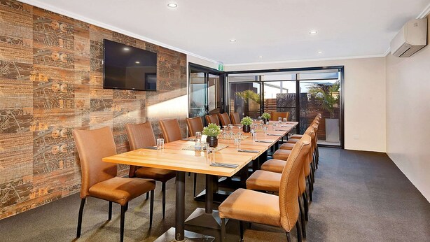 A conference room with a long table, leather chairs, and a TV mounted on the wall. - Comfort Inn Whyalla (Whyalla Playford)
