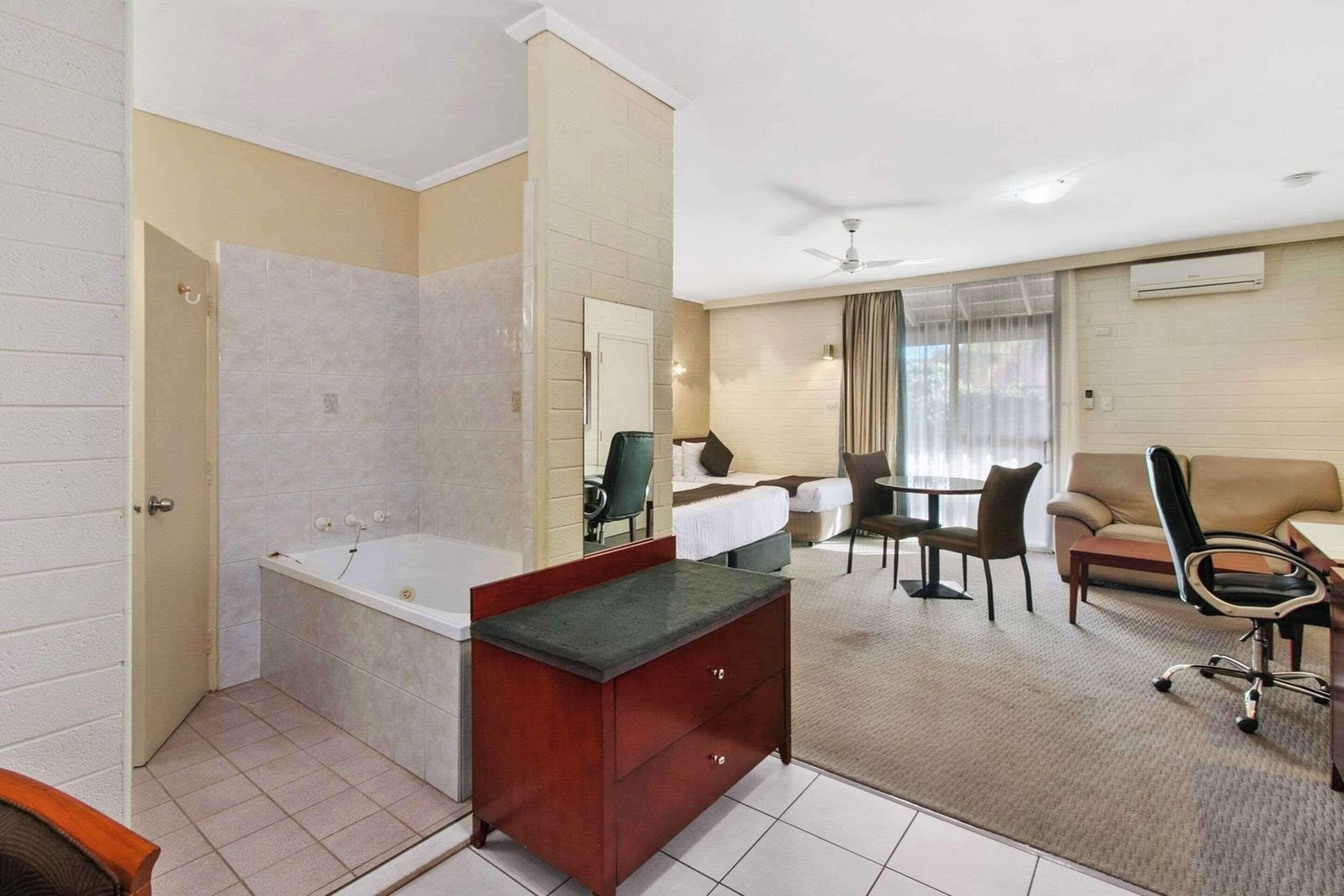Una habitación de hotel con baño, comedor y sala de estar.