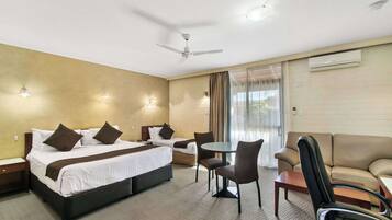Hotelkamer met een bed, twee stoelen, een kleine tafel, een bank, een plafondventilator en een airconditioning.