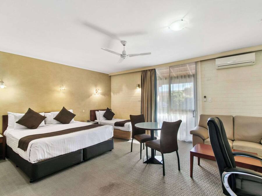 Hotelkamer met een bed, twee stoelen, een kleine tafel, een bank, een plafondventilator en een airconditioning.