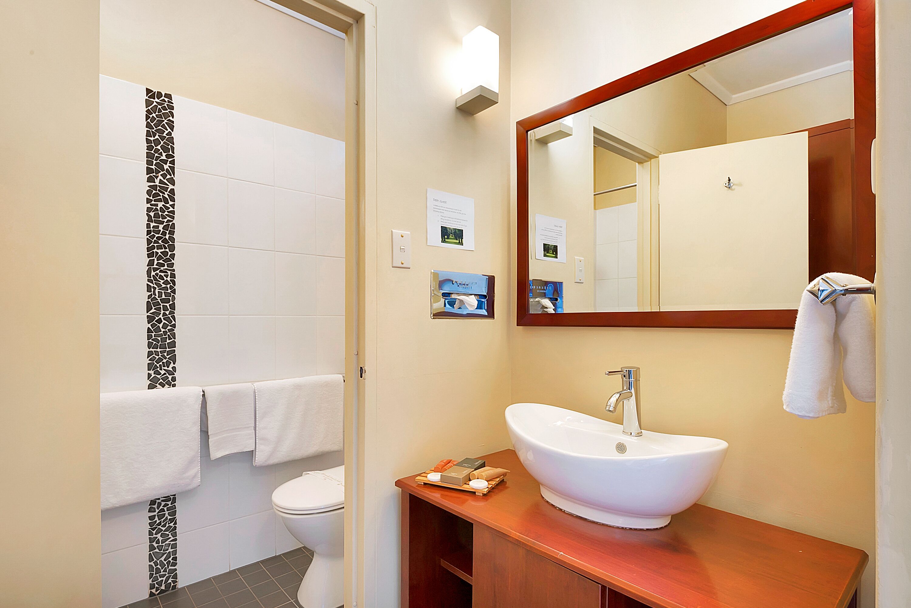 A bathroom with a white sink, a mirror, and a toilet.