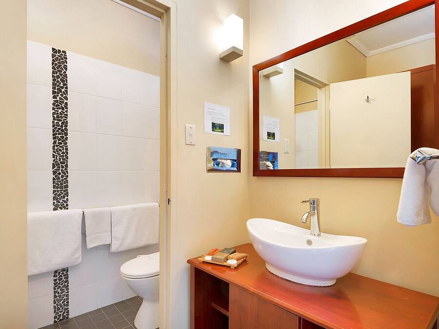 A bathroom with a white sink, a mirror, and a toilet.