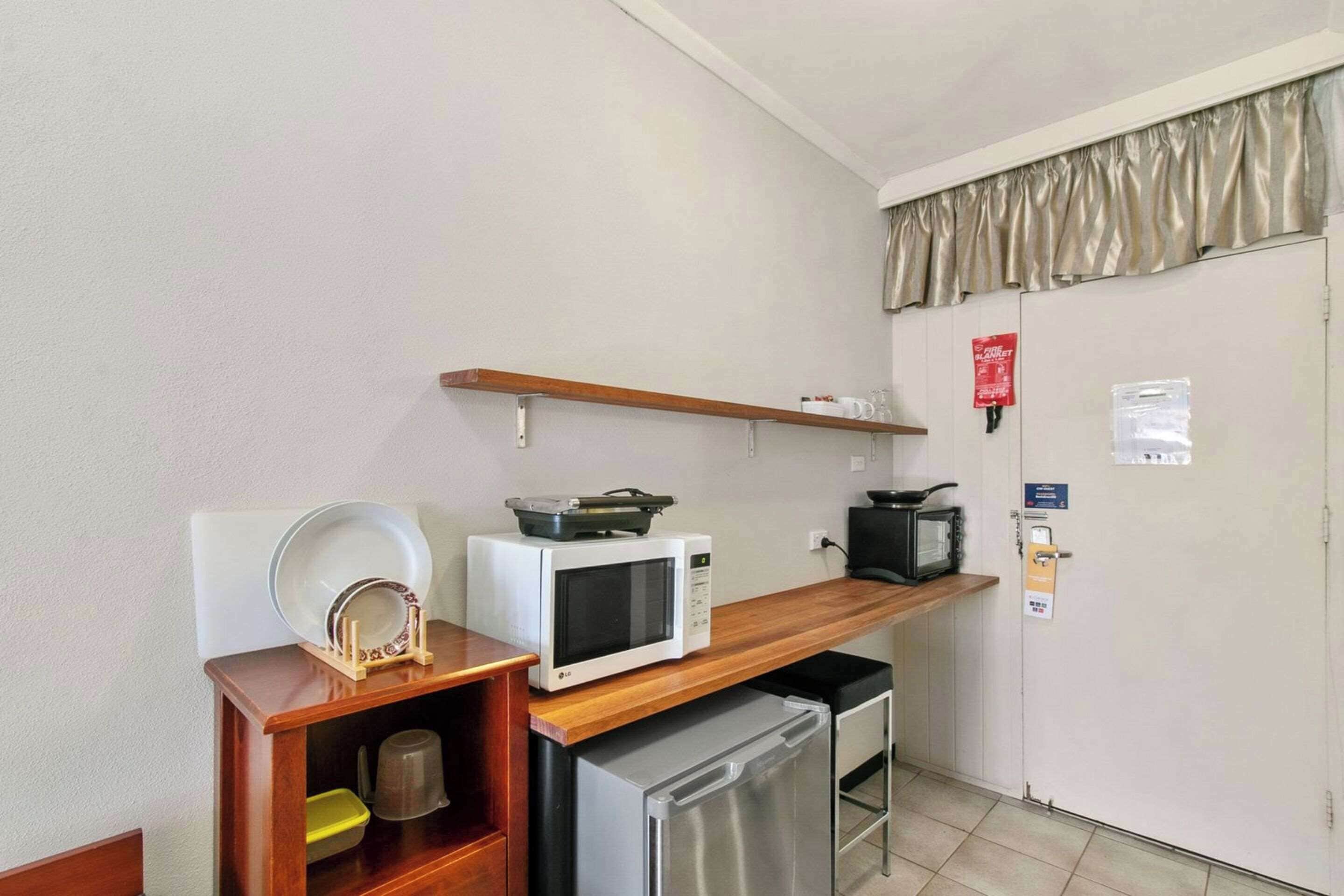 Una kitchenette compacta equipada con microondas, tostadora y refrigerador pequeño.