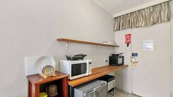 Una kitchenette compacta equipada con microondas, tostadora y refrigerador pequeño.
