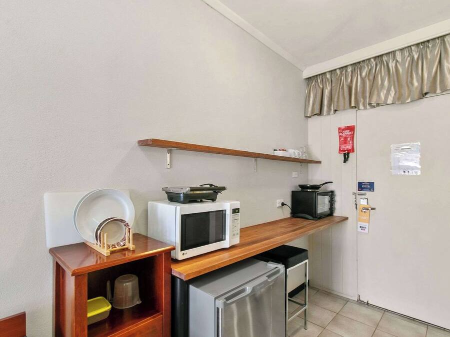 Una kitchenette compacta equipada con microondas, tostadora y refrigerador pequeño.