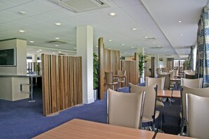 Een moderne hotellobby met een receptiebalie, zitgedeeltes en decoratieve houten panelen.