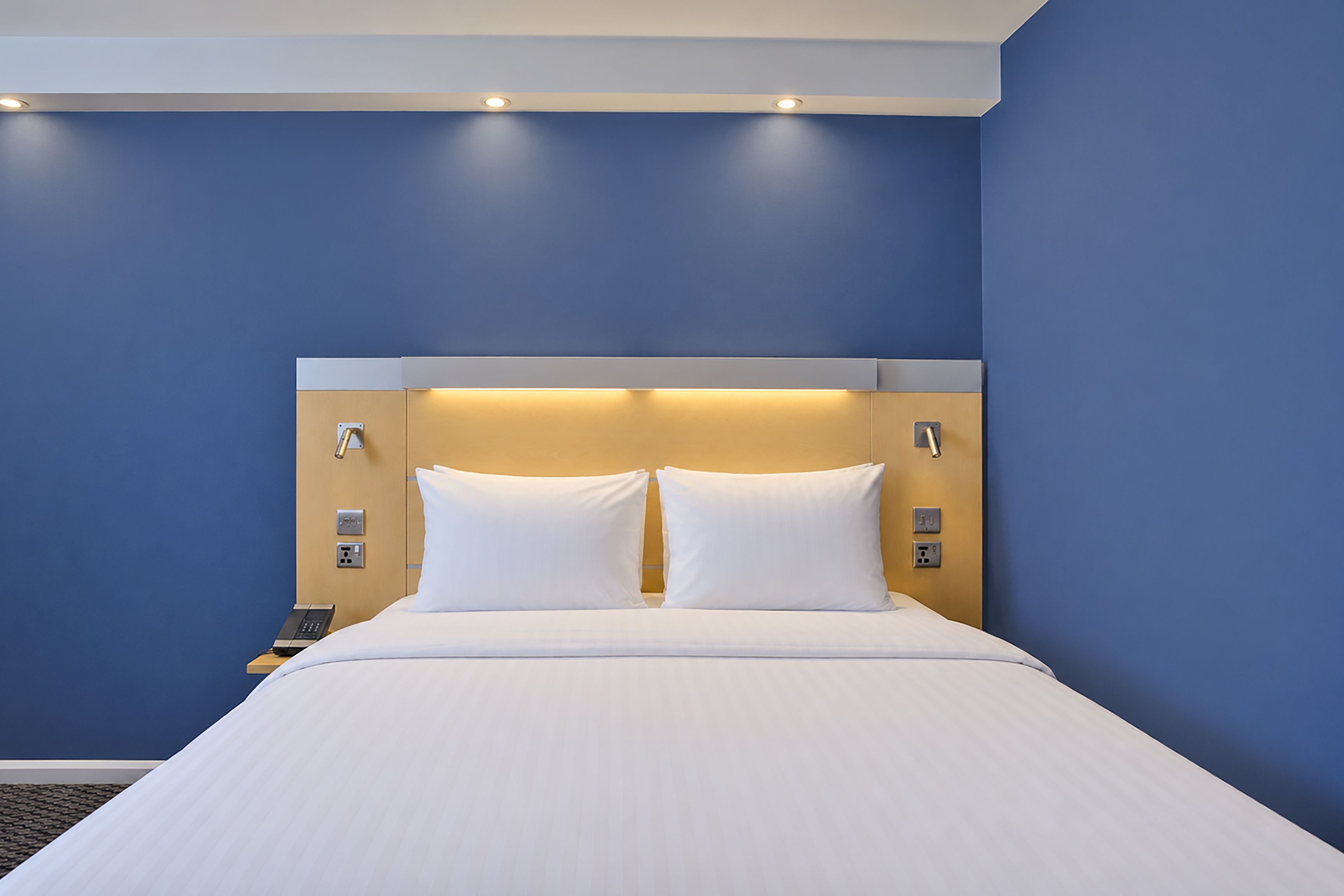 A hotel room with a large bed, two bedside tables, and a wall-mounted telephone.