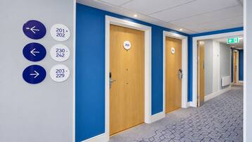 Un pasillo con puertas numeradas 201, 203, 204 y 229, y flechas que señalan direcciones.