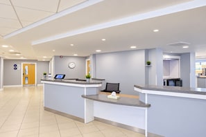 A reception area with a reception desk, a clock, and a plant. - Cardiff Airport Hotel by Belvilla (Barry)
