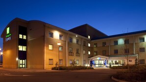 Un hôtel Holiday Inn Express au design moderne, avec plusieurs étages et une entrée bien éclairée.