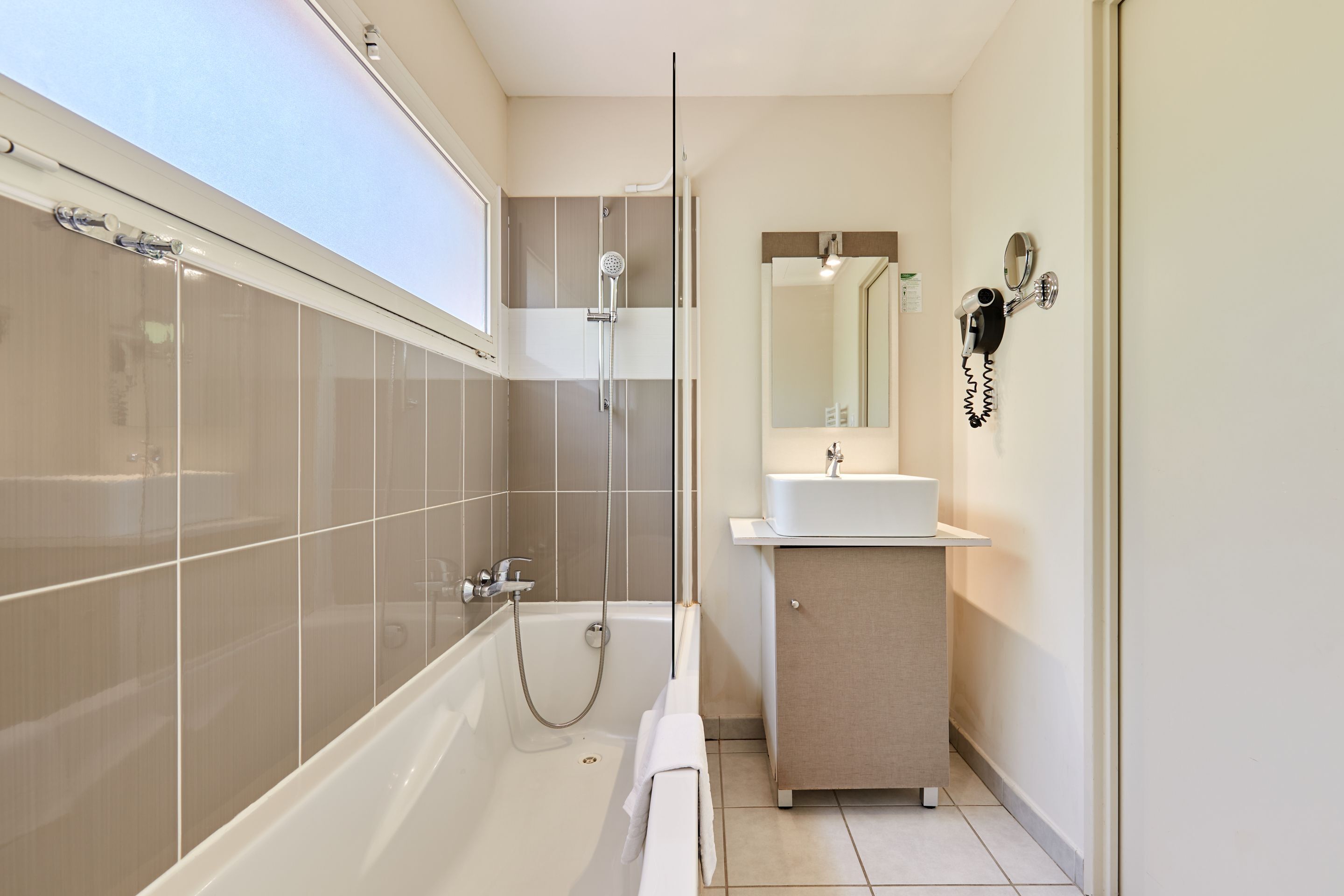 A modern bathroom with a bathtub, shower, and vanity.