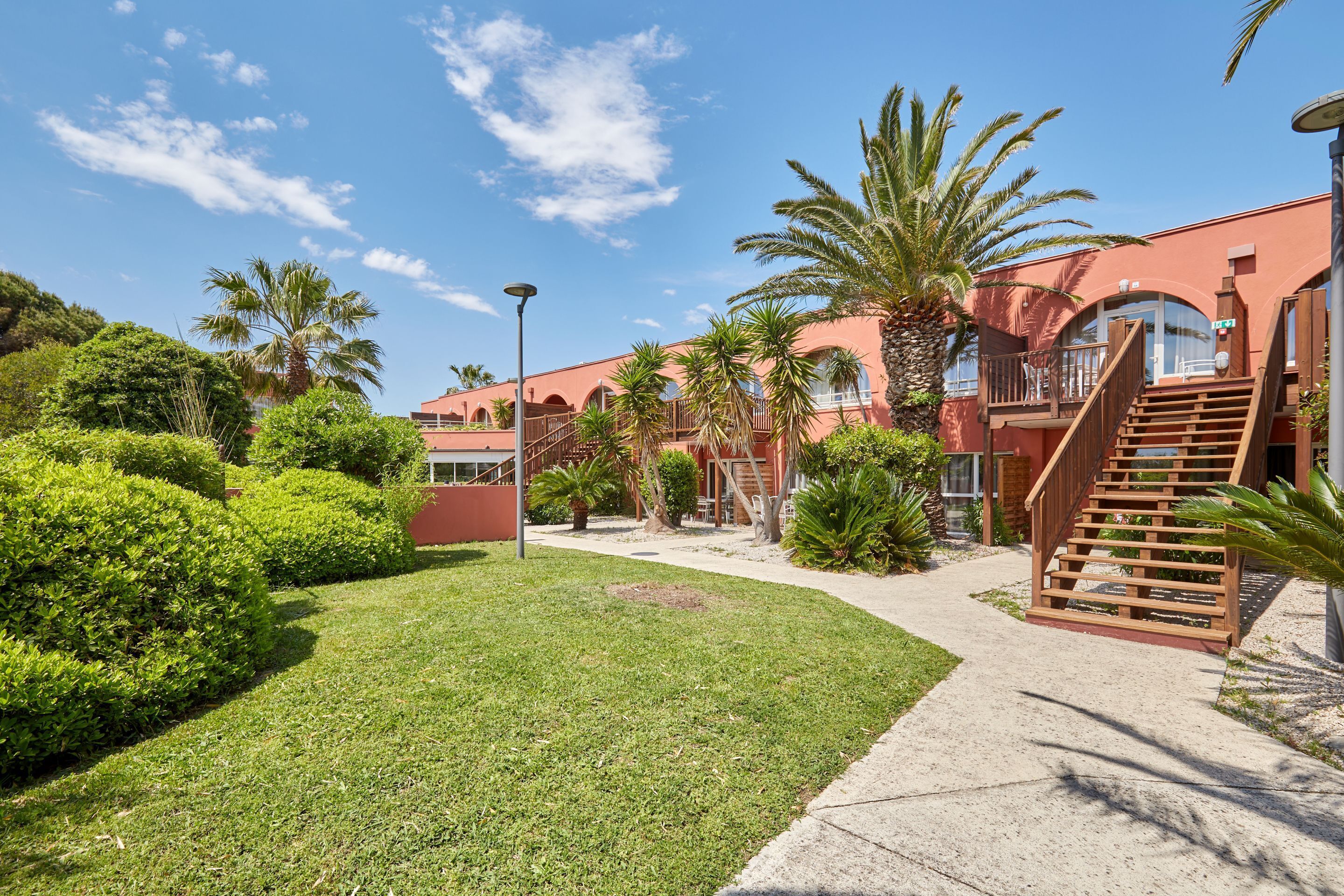 A courtyard with a palm tree, a staircase, and a building with arched windows.