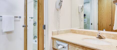Un baño con puerta de madera, un lavabo con espejo y un perchero para toallas.