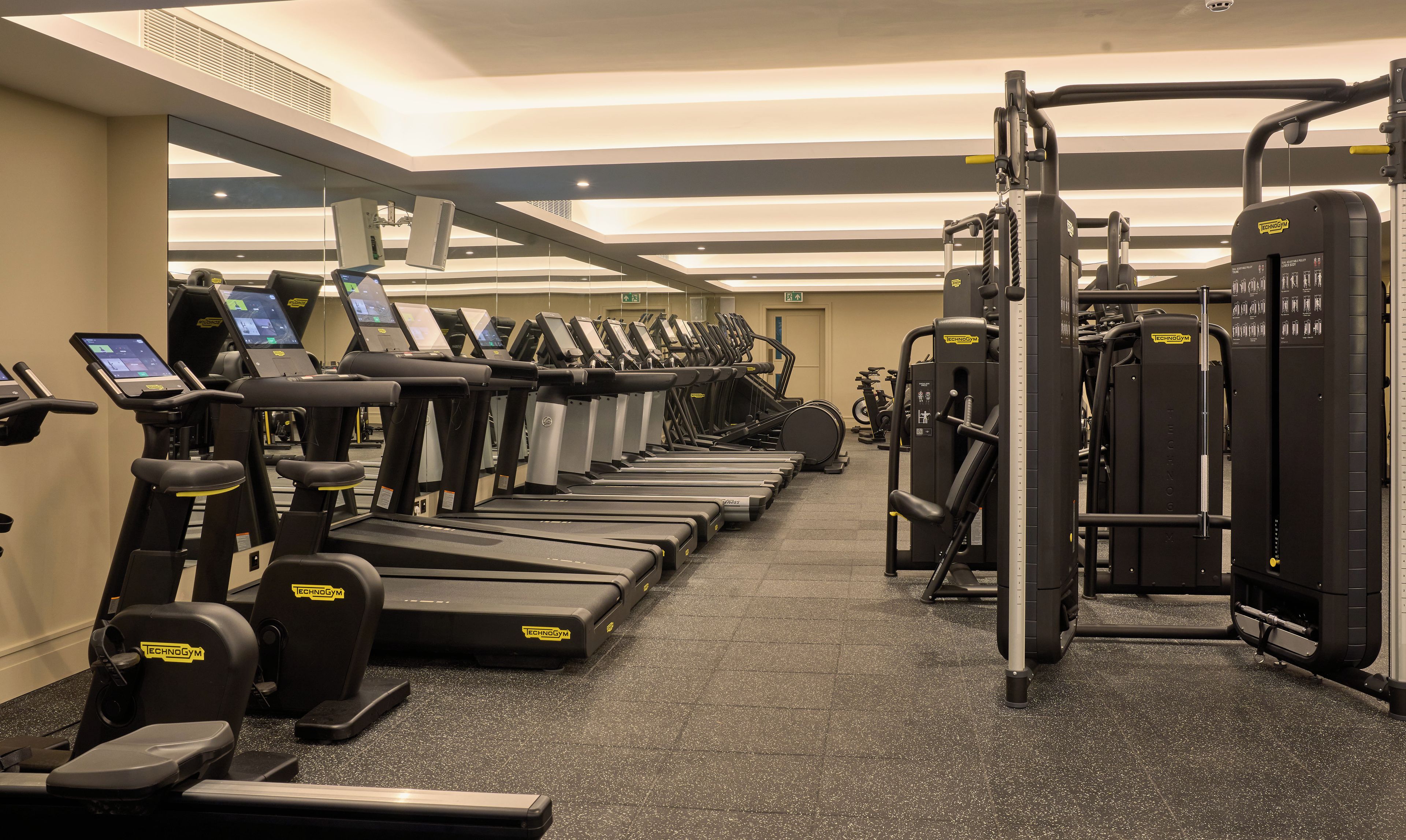 Un gimnasio con cintas de correr, bicicletas estáticas y máquinas de pesas.