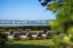 A marina with numerous sailboats and yachts docked. There are several lounge chairs arranged on the grass in the foreground. - The NICI New Forest (Lymington)