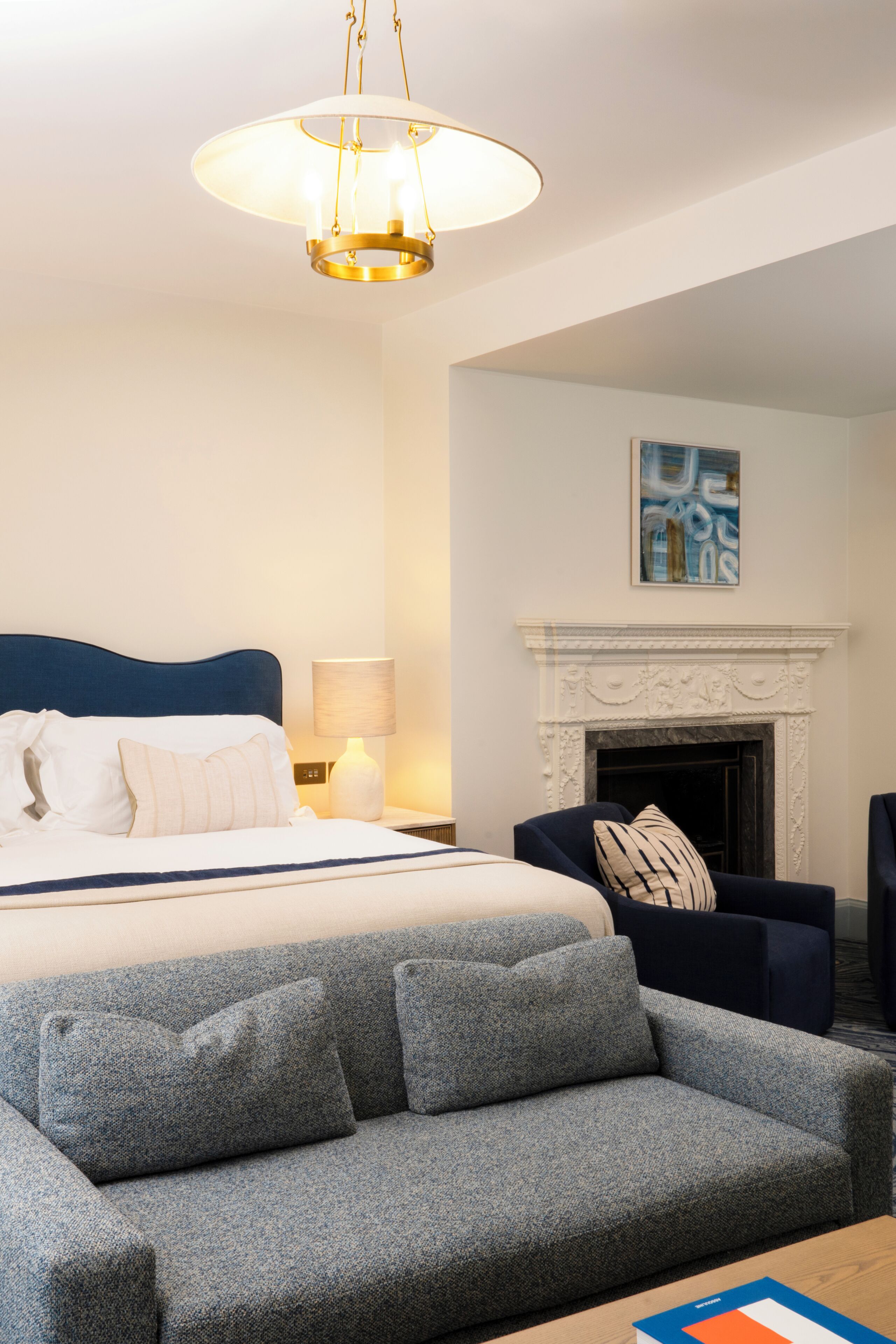 Une chambre d’hôtel avec un lit, un canapé, une cheminée et un tableau au mur.