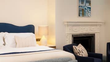 Una habitación de hotel con cama, sofá, chimenea y un cuadro en la pared.