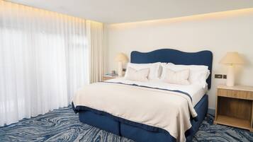 A hotel room with a bed, two bedside tables, a nightstand, a lamp, and a window with curtains.
