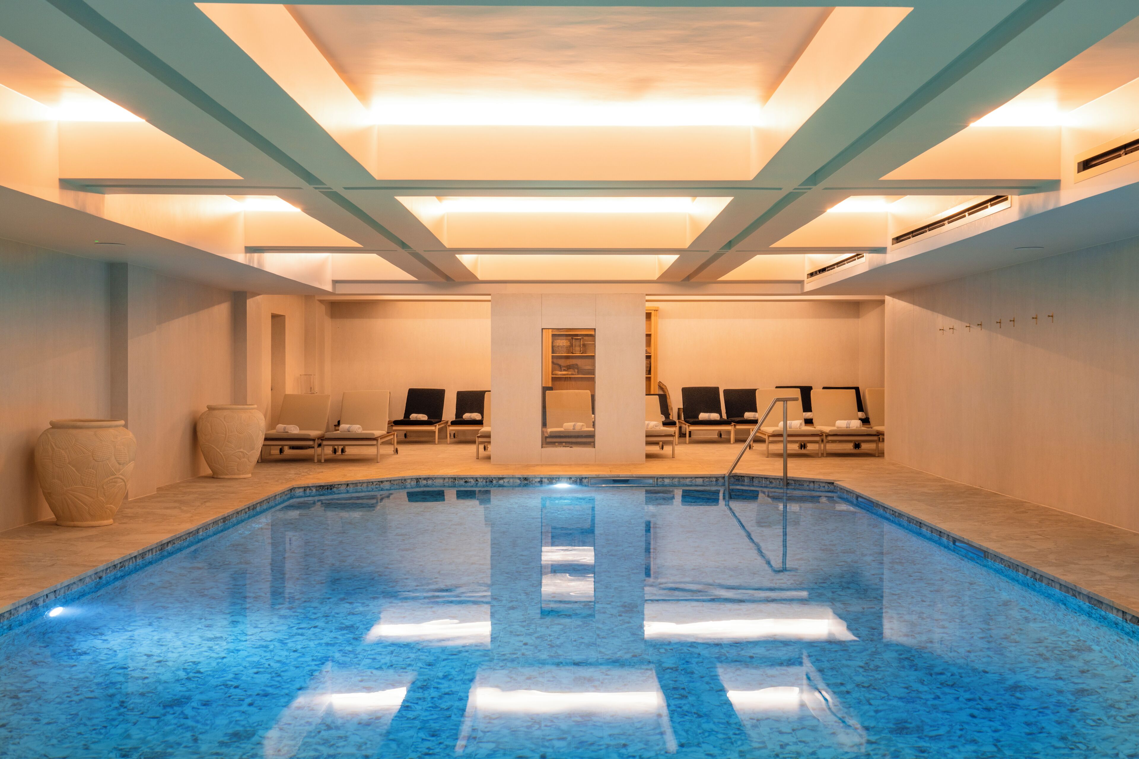 A swimming pool with lounge chairs and a large vase.