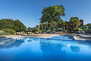 Relax by the serene pool surrounded by lush greenery and comfortable seating options.