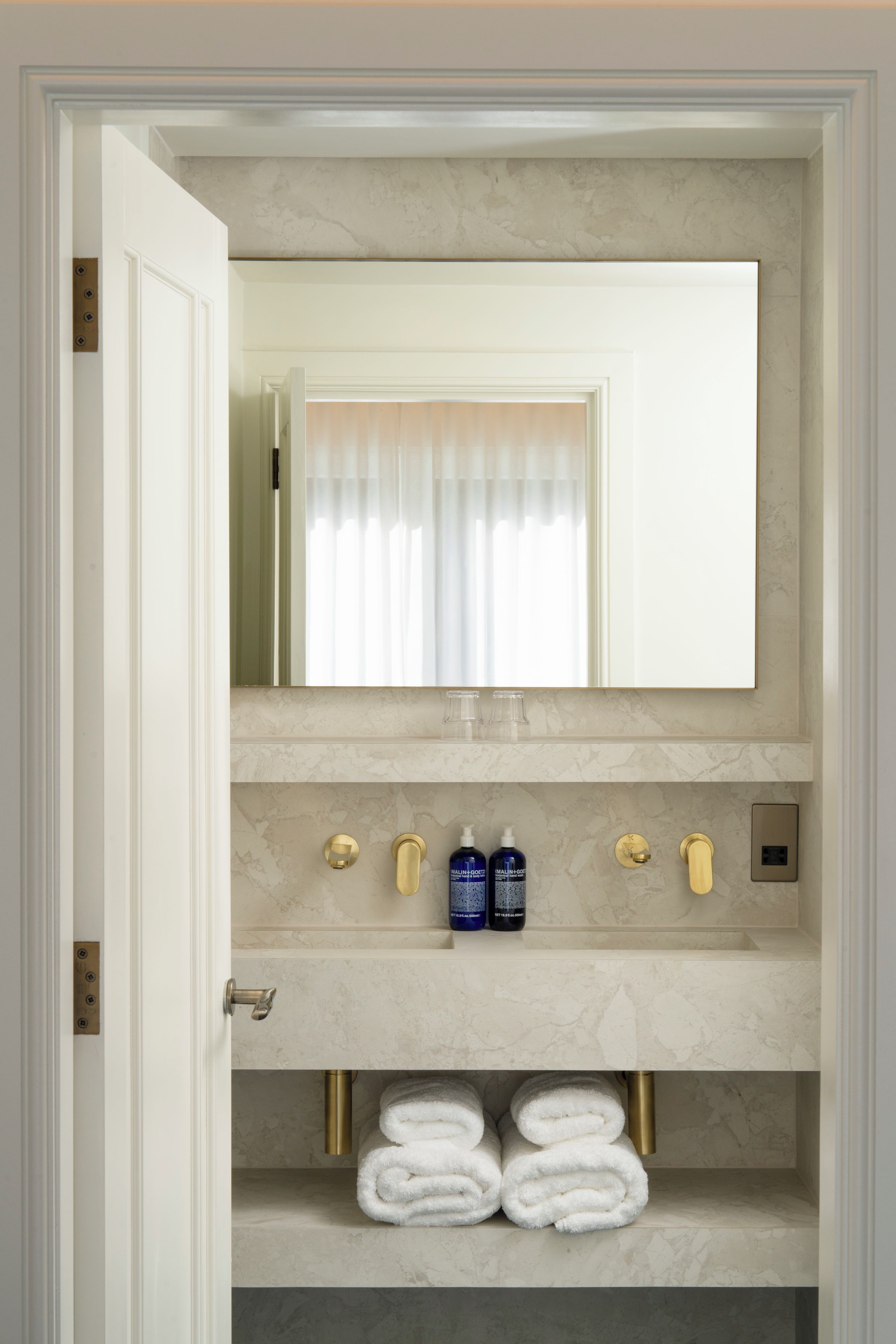 A bathroom with a marble countertop, a mirror, a towel rack, and toiletries.