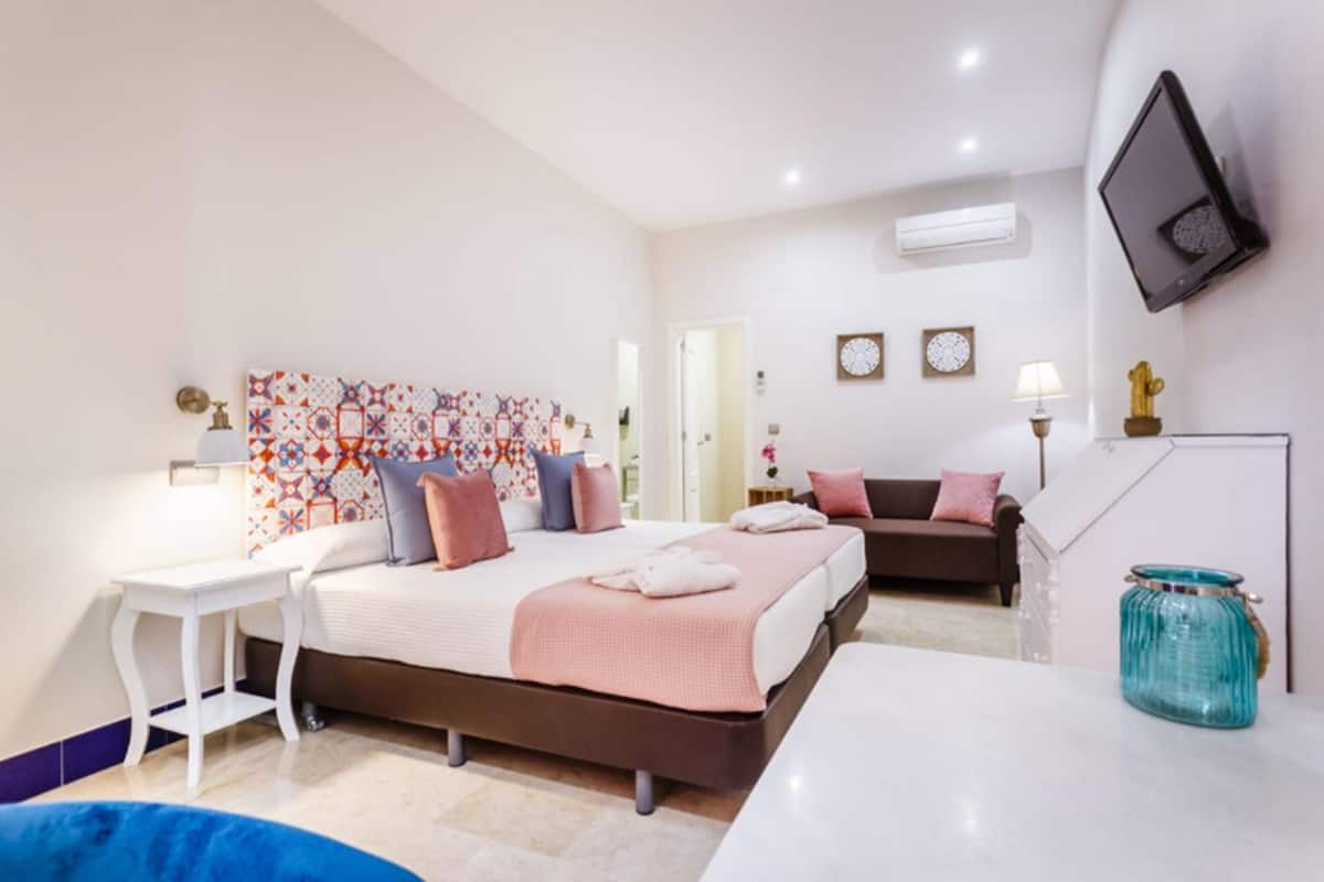 Une chambre d’hôtel moderne équipée d’un grand lit, d’un bureau, d’un canapé et d’un téléviseur fixé au mur.