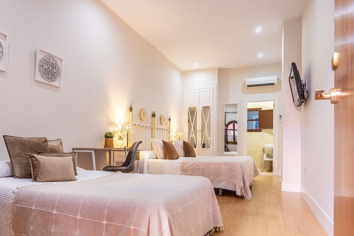 Une chambre d’hôtel avec deux lits, un bureau, une chaise, un miroir et une porte donnant sur une salle de bain.