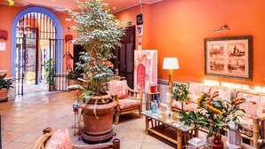 A spacious lobby with a high ceiling, ornate railings, and a central seating area with a coffee table and chairs. - Hotel Patio de la Alameda (Seville)