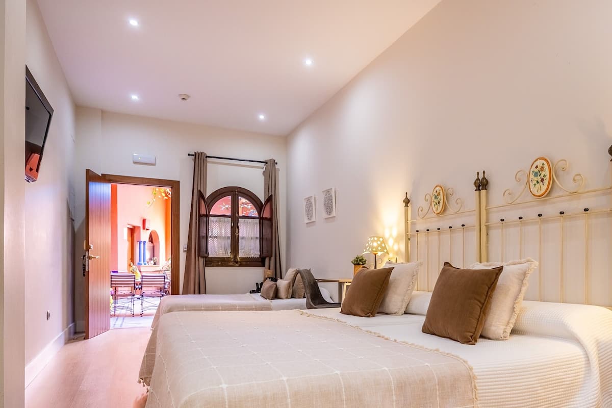 Une chambre d’hôtel avec deux lits, une table de chevet avec une lampe, une armoire et une fenêtre avec des rideaux.