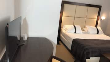 Una habitación de hotel con cama, mesita de noche con televisor de pantalla plana y una silla.